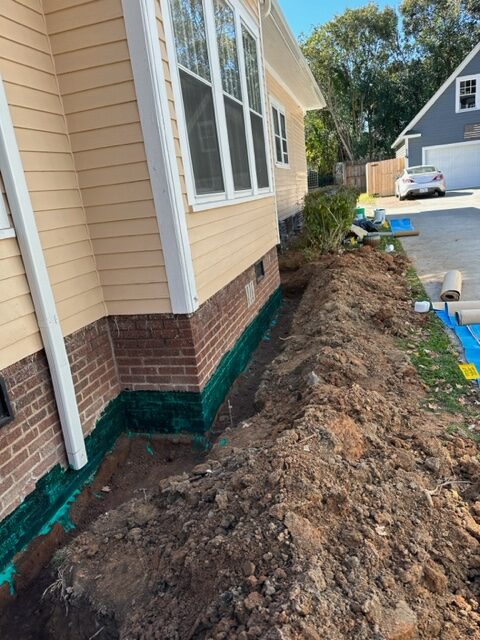 A house's foundation, with exterior foundation waterproofing being done.
